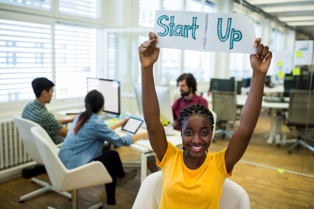 lady holding up a notebook written startup